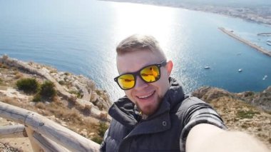 Genç adam seyahat selfie trekking geziye alarak gün. Kayalar ve deniz arka planı
