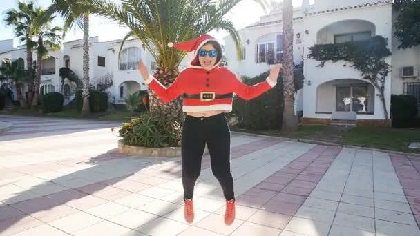 Concepto de Navidad y la gente - niña feliz en sombrero de invierno cerca del árbol que se divierten al aire libre — Vídeo de stock