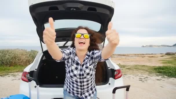 Glad ung kvinna på sommaren resa semester sitter i en bil stam — Stockvideo