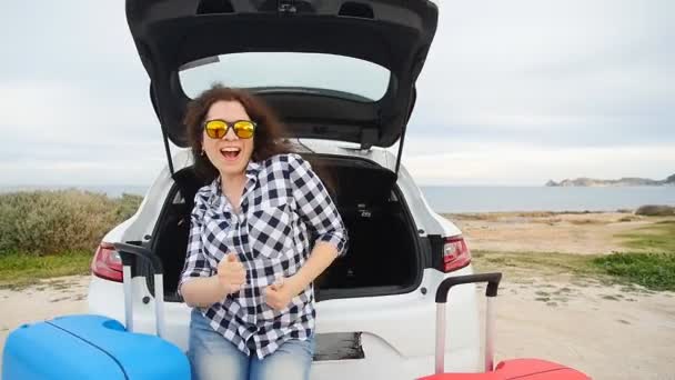 Jovem feliz em férias de viagem de verão sentado em um tronco de carro — Vídeo de Stock