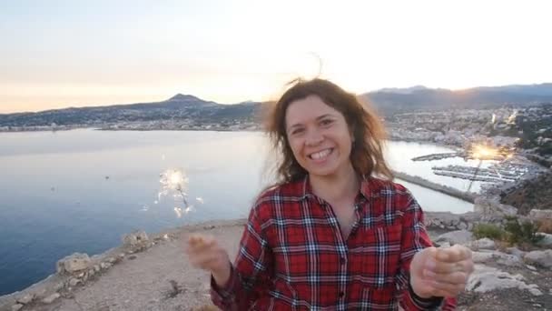 Jovem feliz sorrindo mulher segurando sparkler perto do mar — Vídeo de Stock