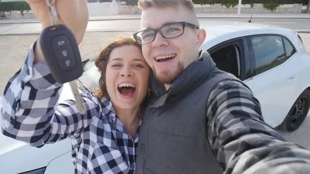 Щаслива пара показує ключі, що стоять біля машини — стокове відео