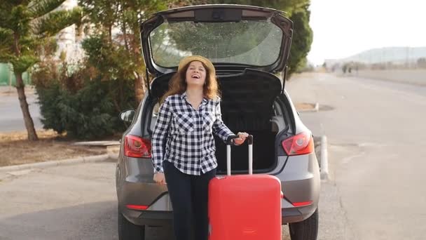 Beautiful young traveler woman with suitcase near car trunk — Stock Video