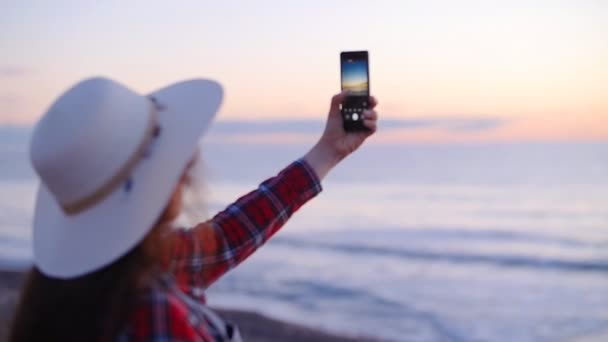 Νεαρή γυναίκα τουριστικά λαμβάνοντας εικόνες από το ηλιοβασίλεμα ή την αυγή από τη θάλασσα — Αρχείο Βίντεο