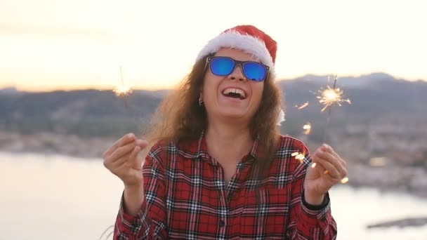 Jovem mulher no Natal ou casaco de ano novo e chapéu segurando férias de inverno sparkler e fogo de bengala ao ar livre — Vídeo de Stock