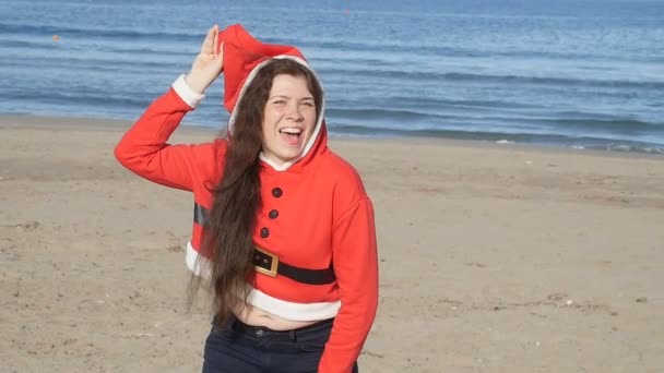 Fröhliche junge Frau mit Weihnachtsmann-Hut tanzt draußen — Stockvideo