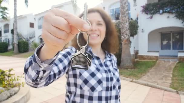 Счастливая молодая женщина переезжает в новый дом. Показать ключи от новой недвижимости — стоковое видео