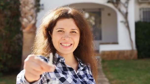 Mujer joven y feliz mudándose a un nuevo hogar. Mostrando las llaves de la nueva propiedad — Vídeos de Stock