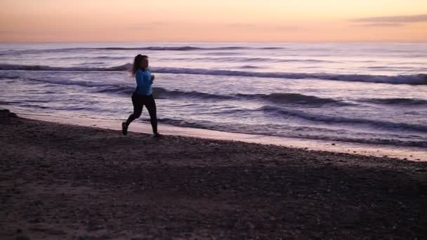 Kobieta działa na plaży o zachodzie słońca. Koncepcja fitness — Wideo stockowe