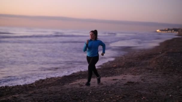 Mujer corriendo en la playa al atardecer. Concepto Fitness — Vídeos de Stock