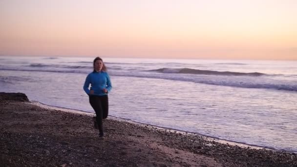 Donna che corre in spiaggia al tramonto. Concetto fitness — Video Stock
