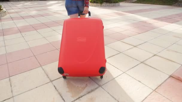 Mulher de salto com uma mala vermelha correndo em um resort — Vídeo de Stock