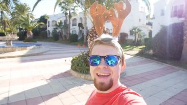 Mutlu Noel geyik boynuzları selfie genç adam gülümsüyor. Noel kavramı