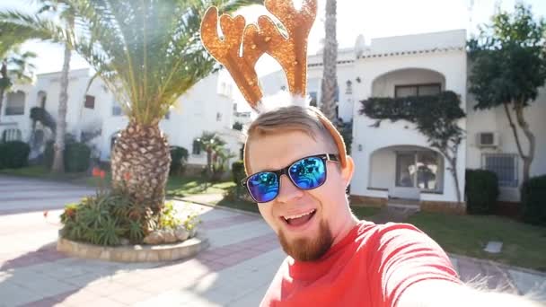 Happy glimlachend jongeman in Kerstmis herten hoorns selfie. Kerst concept — Stockvideo