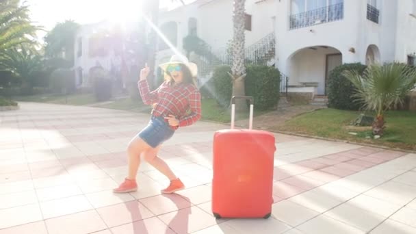 Jovencita feliz con maleta roja llegando al resort o apartamento — Vídeos de Stock