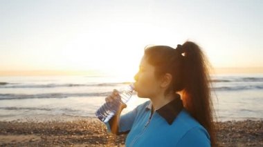Genç sportif kadın içme suyu açık deniz kenarında Sunset'teki