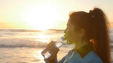 Genç sportif kadın içme suyu açık deniz kenarında Sunset'teki