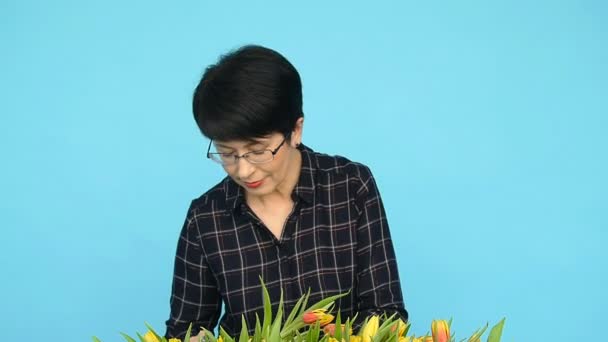 En medelålders kvinna med blommor. Begreppet blomsterhandlare — Stockvideo