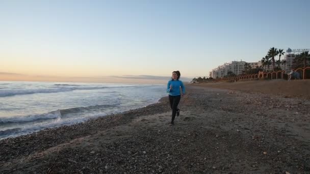 Mujer corriendo cerca del mar al atardecer — Vídeos de Stock