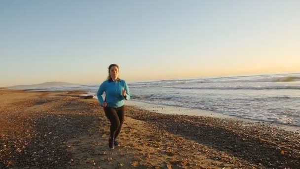 Mujer corriendo cerca del mar al atardecer — Vídeos de Stock