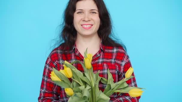 Mujer joven con tulipanes sobre fondo azul — Vídeo de stock