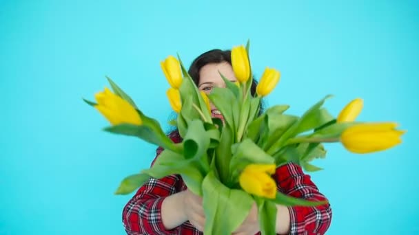 Mujer joven con tulipanes sobre fondo azul — Vídeos de Stock