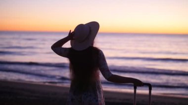 Genç kadın deniz kenarında gün batımında şapkalı. Tatil kavramı