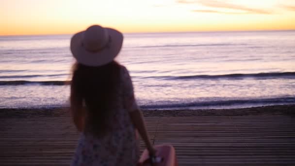 在日落附近的海边的年轻女子帽子。假期概念 — 图库视频影像
