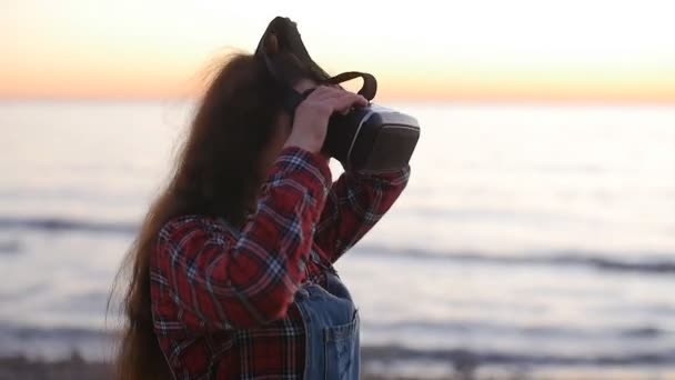 Genç kadın bir sanal gerçeklik gözlük günbatımı kullanır. — Stok video