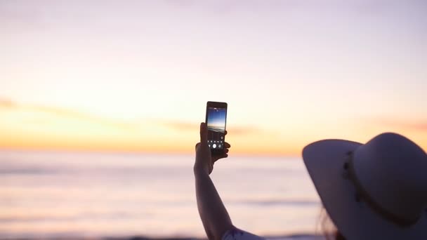 Giovane donna scattare foto con il suo smartphone sulla spiaggia — Video Stock