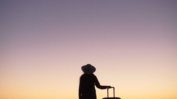 Silhouette einer Frau mit einem Koffer am Strand bei Sonnenuntergang — Stockvideo