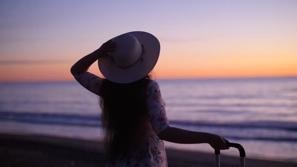 Junge schöne Frau mit Hut und großem Koffer am Strand — Stockvideo