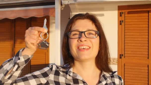 Glücklich lächelnde Frau mit dem Hausschlüssel ihres neuen Hauses — Stockvideo