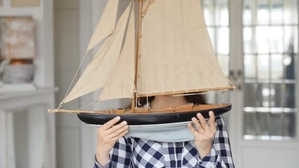 Een gelukkige jonge vrouw houdt een model van een zeilschip — Stockvideo