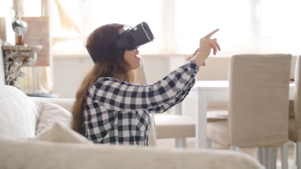 Młoda kobieta siedzi na kanapie w domu zestaw wirtualnej rzeczywistości — Wideo stockowe