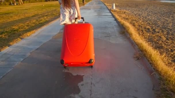 Mujer joven y elegante corriendo con maleta roja. Concepto de vacaciones — Vídeo de stock