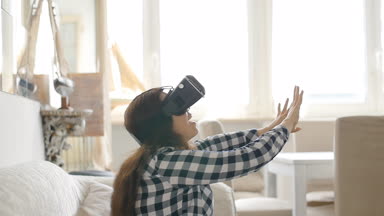 Sanal gerçeklik kulaklık veya 3d gözlük evde koltukta oturan genç kadınla