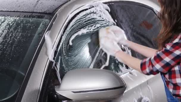 Молодая женщина моет машину губкой — стоковое видео