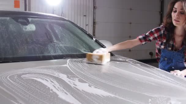 Jonge vrouw wassen van een auto met een spons — Stockvideo