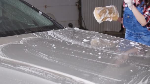 Młoda kobieta, mycia samochodu z gąbką — Wideo stockowe