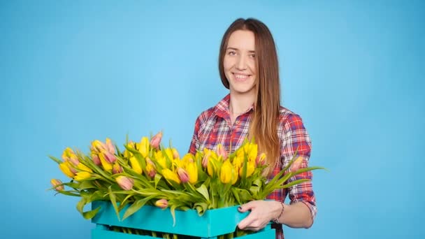 Cheerful young woman florist holding box of tulips — Stock Video