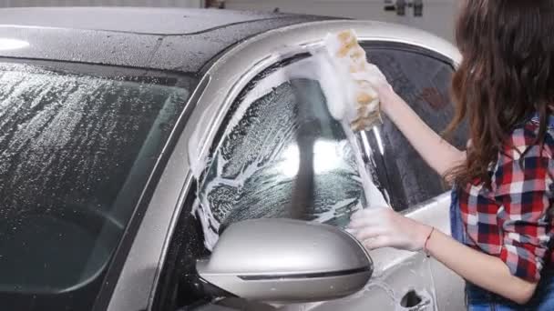 Jeune femme lave la voiture avec une éponge — Video
