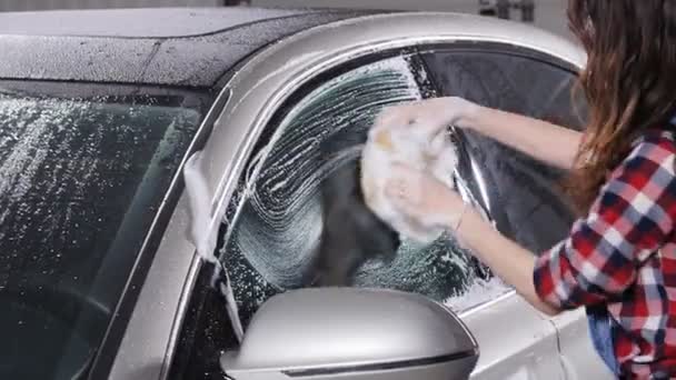 Jovem mulher lava o carro com uma esponja — Vídeo de Stock