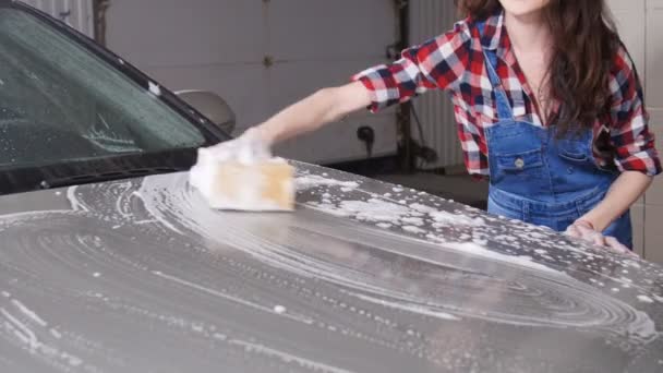Mujer joven lava el coche con una esponja — Vídeos de Stock
