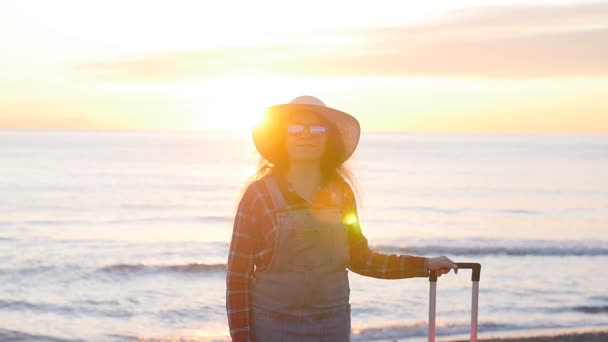 Jonge vrouw met een koffer op het zonnige strand — Stockvideo