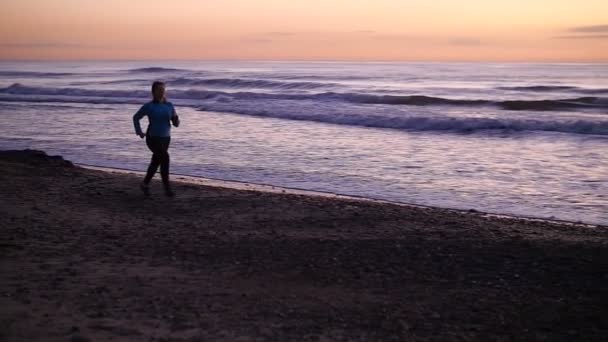 Jeune femme coureuse un jogging sur la plage — Video