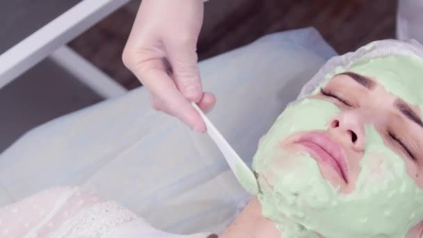 Schoonheid en kosmetologie concept. Jonge vrouw met crème masker in een schoonheidssalon — Stockvideo