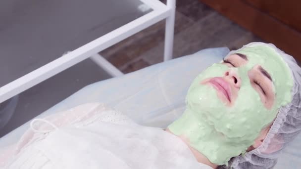 Concepto de belleza y cosmetología. Mujer joven con máscara de crema en un salón de belleza — Vídeos de Stock
