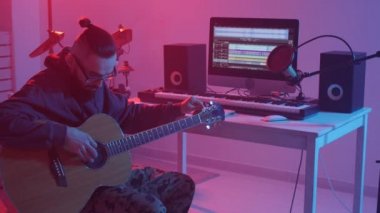 Hobi anlayışı ve müzik yapma. Genç sakallı adam bir müzik stüdyosunda gitar çalıyor.