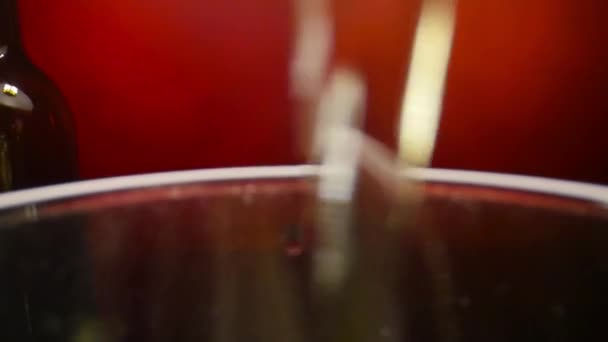 Vino bianco versato in un bicchiere di vino su sfondo rosso al rallentatore — Video Stock